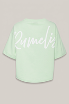 Elias Rumelis Patricia T-Shirt in Apple mit weißem Logo-Print, Rückansicht vor warmem Greige-Hintergrund