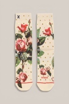 Cremefarbene XPOOS Socken mit Rosenmotiv und goldfarbenen Punkten vor Greige-Hintergrund