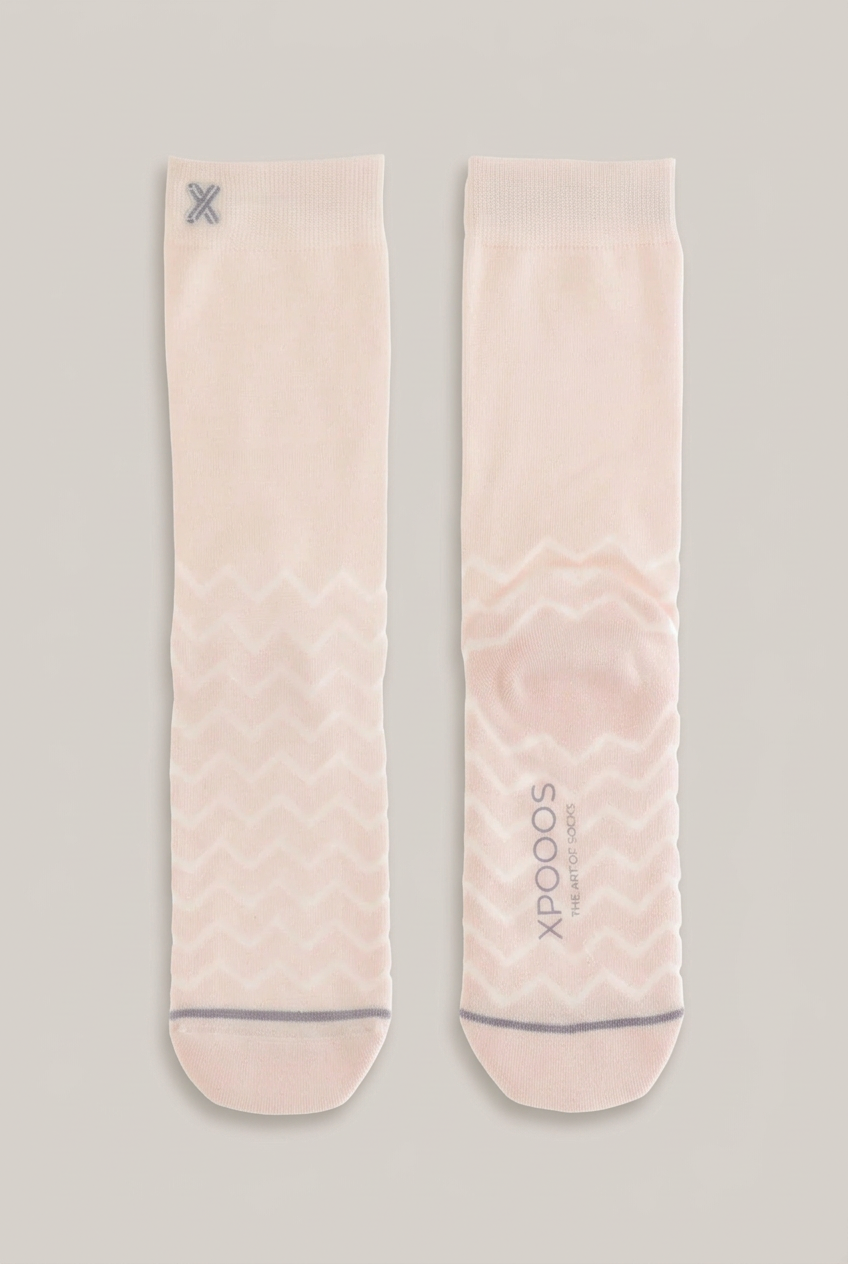 XPOOS Dubai Bamboo Socken in Hellrosa mit Wellenmuster vor warmem Greige-Hintergrund