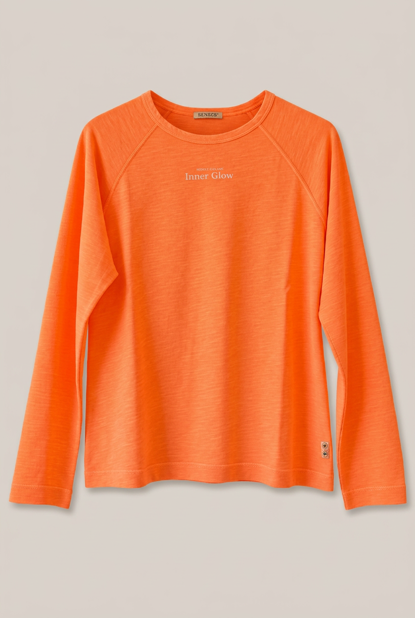 SENCES THE LABEL Glow Hour Langarmshirt in Orange, Vorderseite vor Greige-Hintergrund