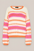 GRACE Pullover mit orange-pinkem Muster vor warmem Greige-Hintergrund