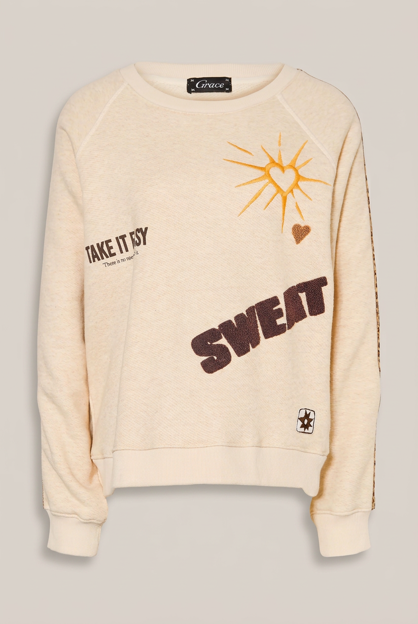 GRACE Sweatshirt in Creme mit Motiven vor warmem Greige-Hintergrund