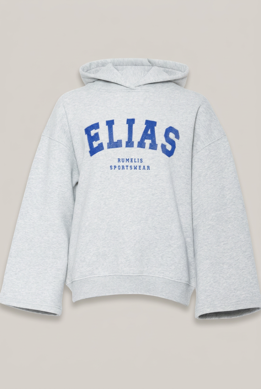 Elias Rumelis ILVIE Hoodie in Nickel Melange mit blauer Perlenstickerei vor warmem Greige-Hintergrund